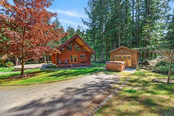 Log cabin with a detached garage and hot tub on a forested lot