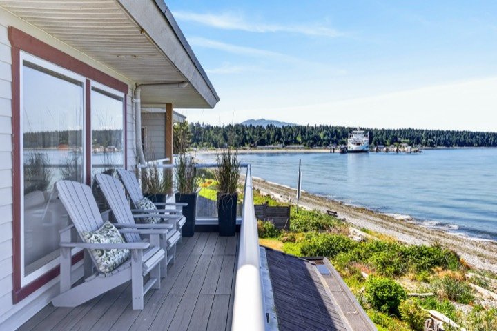 Oceanfront deck with Adirondack chairs and a ferry passing in the distance