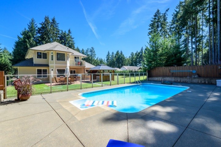 Backyard pool and covered hot tub behind a two-storey home