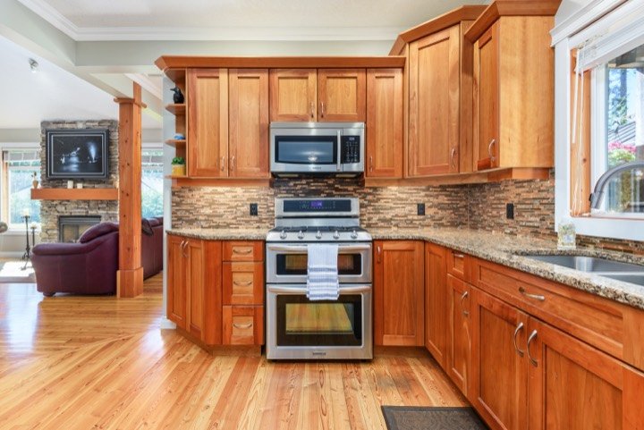 Warm wood kitchen with granite counters open to the living room