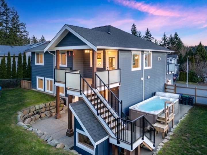 Twilight view of a home with a hot tub and deck